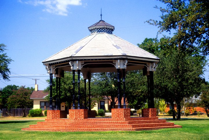 Brick gazebo in a sunny park setting.