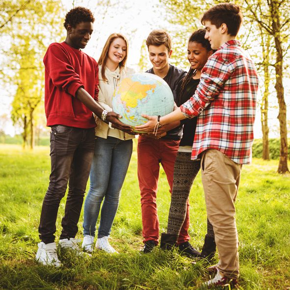 Diverse group holding a globe outdoors.