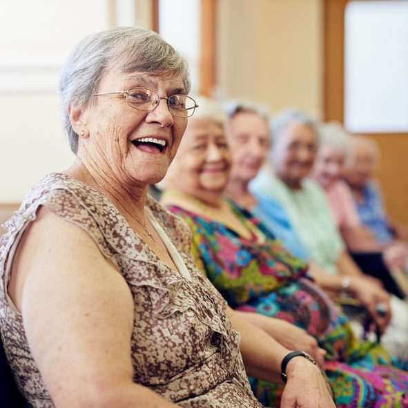 Senior women sitting together, smiling happily.