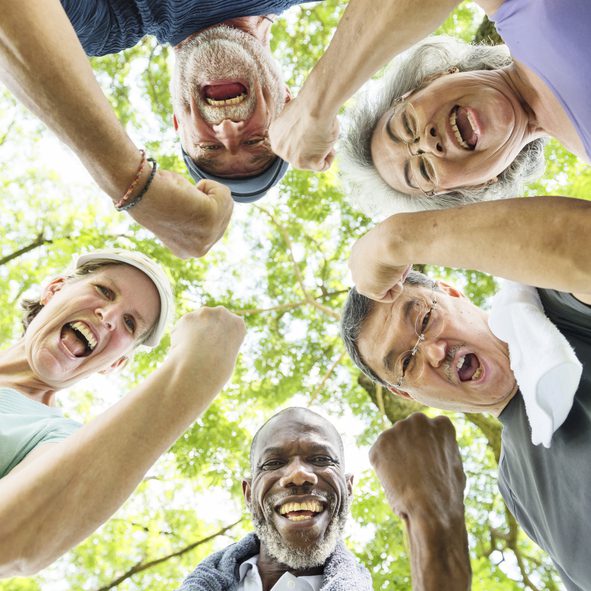 Group of friends celebrating outdoors, smiling upwards.