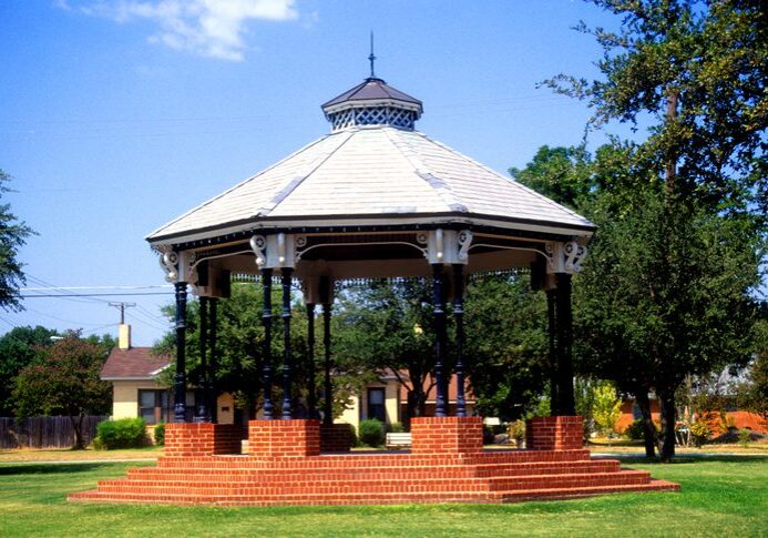 Brick gazebo in a sunny park setting.